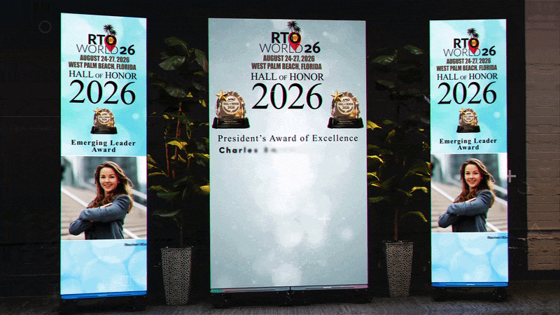Stage with three vertical banners for RT World 2026 Hall of Honor; center panel shows 'President's Award of Excellence' with trophies, side banners show 'Emerging Leader Award' with a woman's photo.